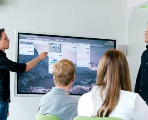 Mitarbeiter im Besprechungsraum analysieren Daten auf einem Monitor