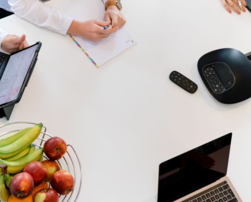 Konferenztisch mit Notebooks, Tablets und Obst